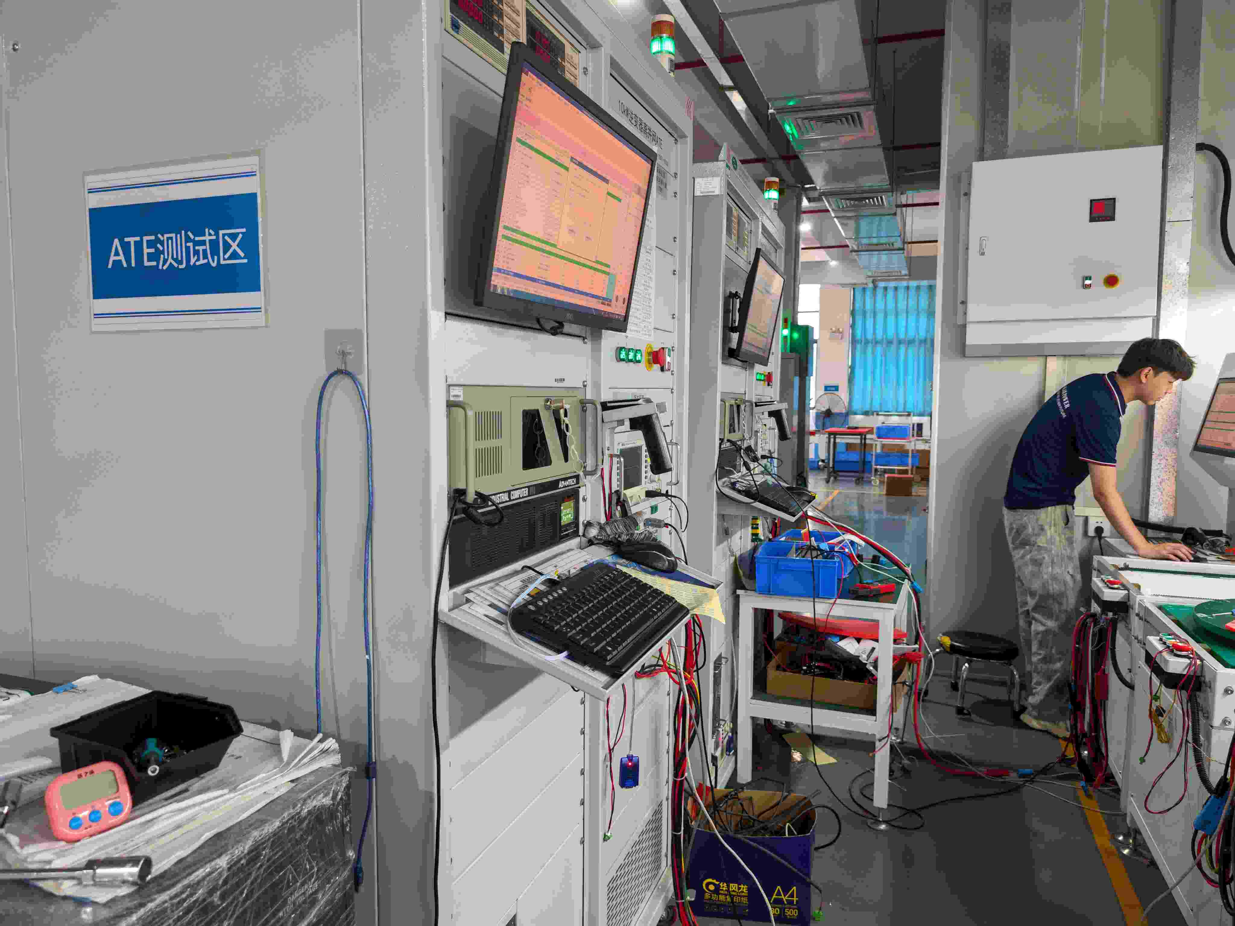 Technician performing automated electrical and functional testing on solar inverters in the SNAT Solar factory.