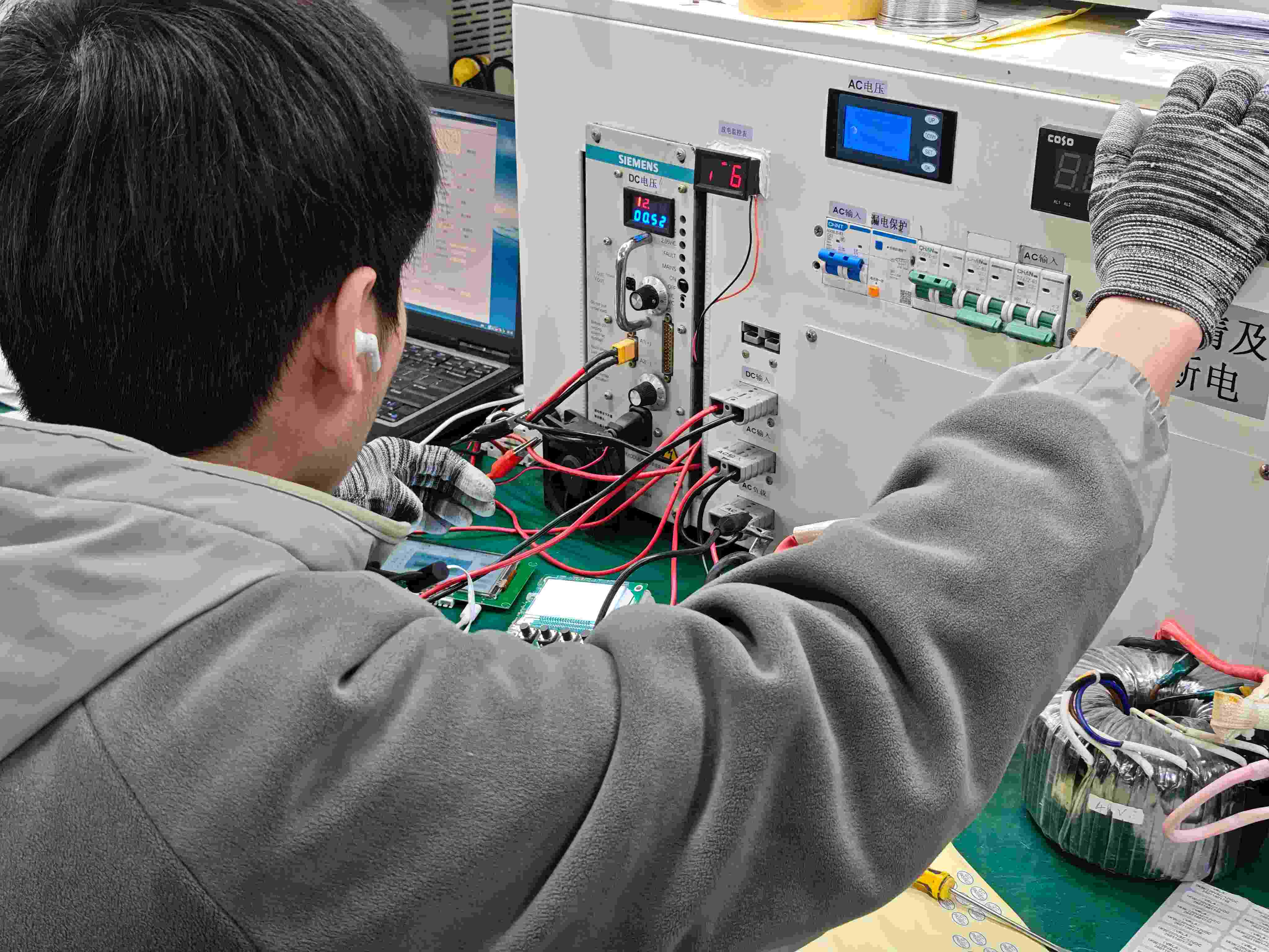 Workers assembling and inspecting solar inverter PCB boards on the SNAT Solar production line.